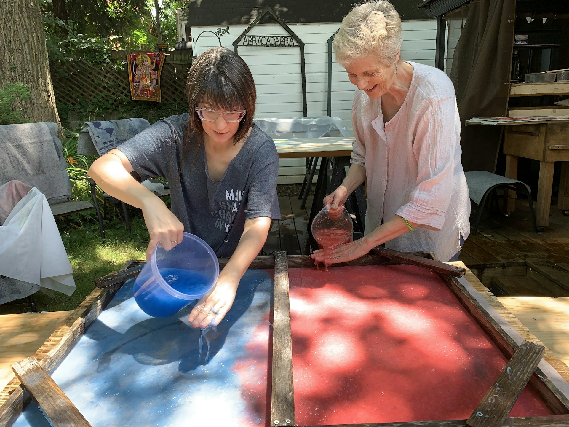 Two women pouring water over paper making session