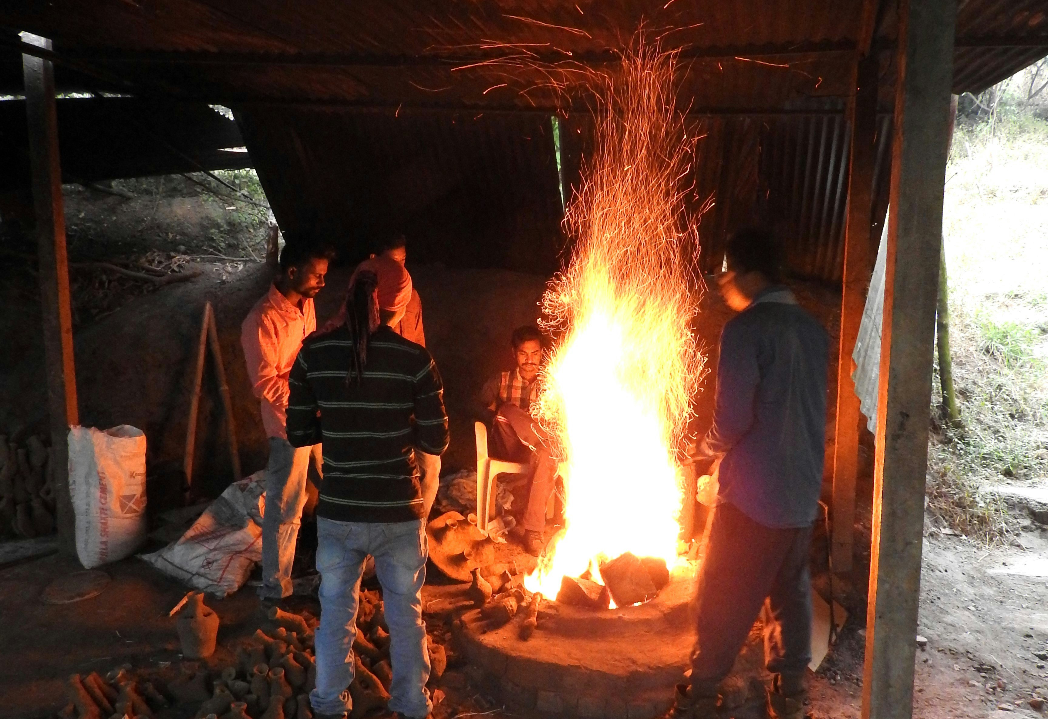 Adivasi craftsmen congregating around the fire pit.