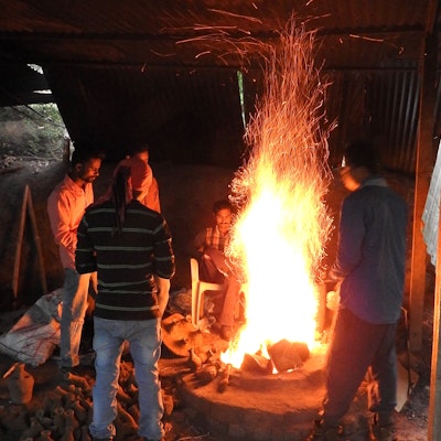 Adivasi craftsmen congregating around the fire pit.