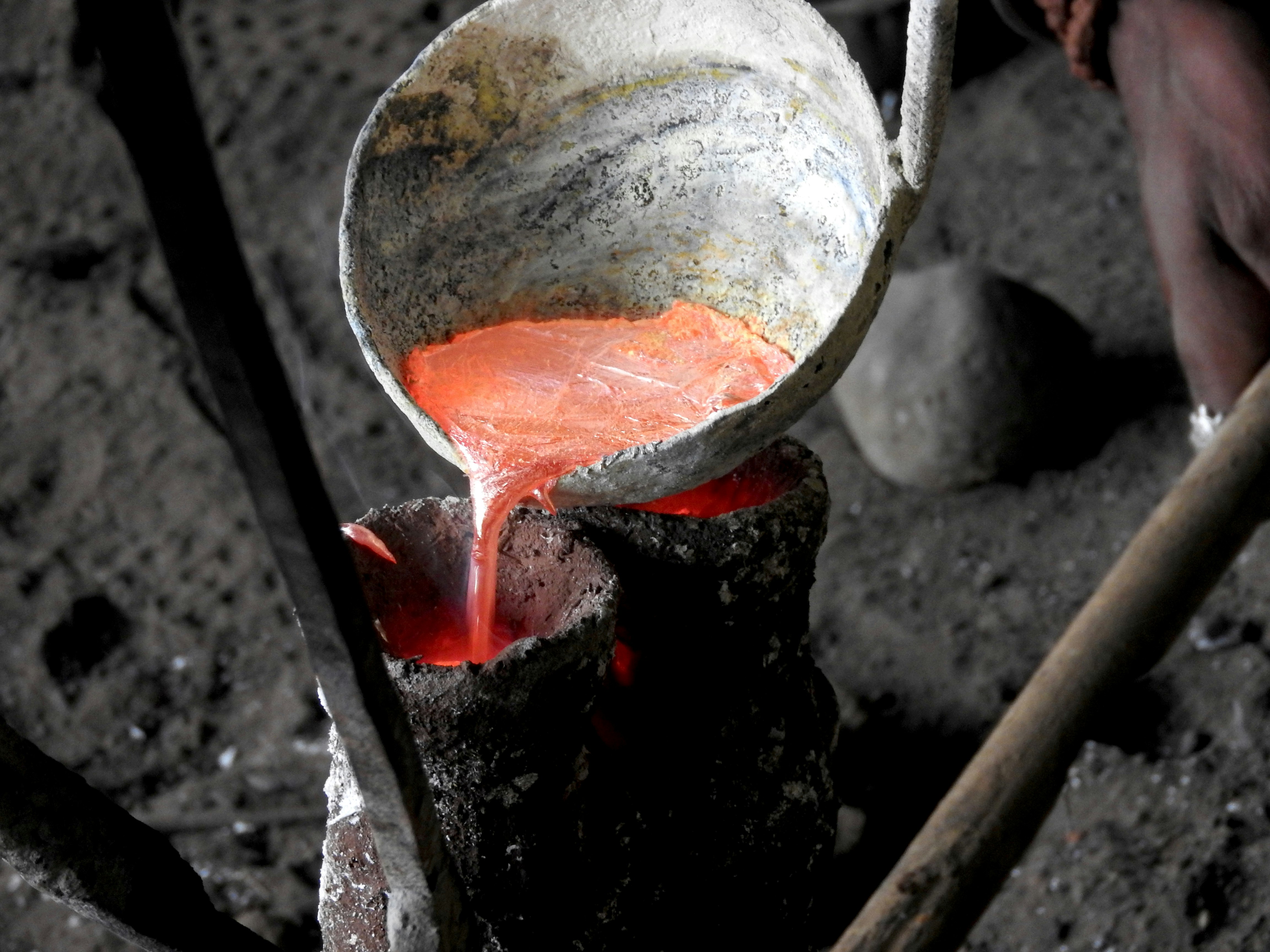 Pouring molten brass carefully into the mold.
