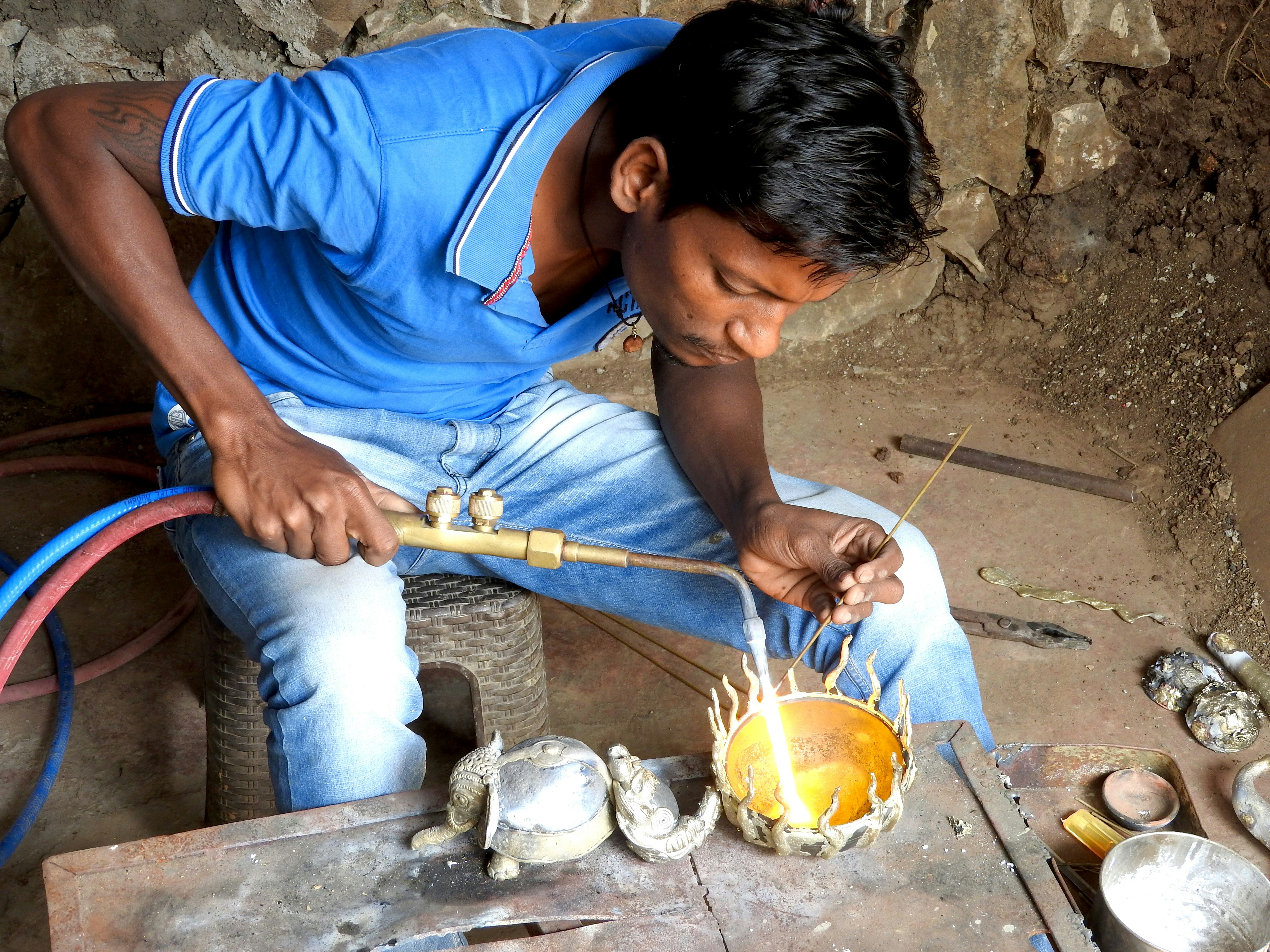 Adivasi crafstman Mahesh repairing any flaws.