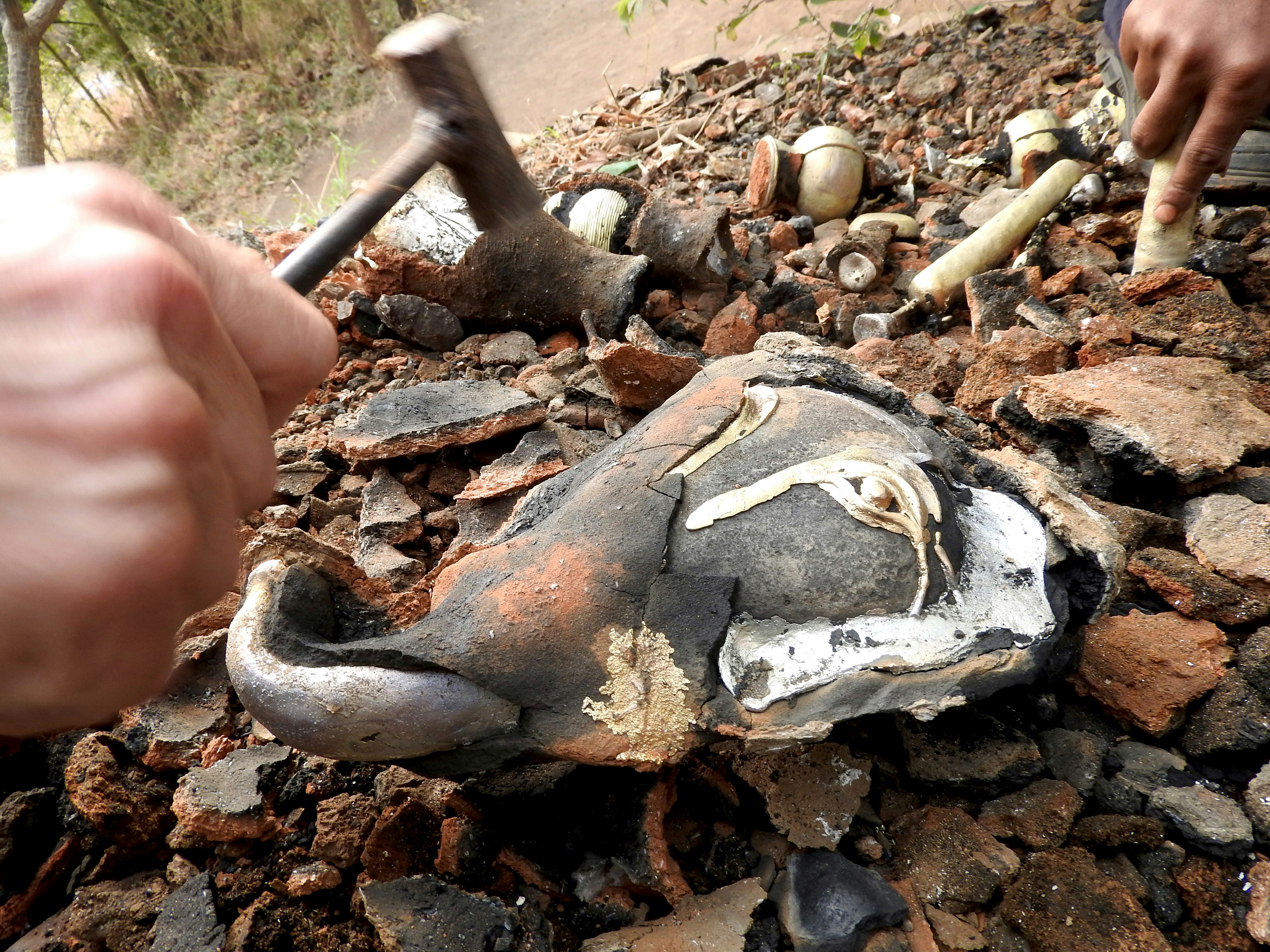 Breaking apart the clay with a small hammer.