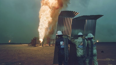 "Oil well fire fighters approach a burning oil well for capping in Al Ahmadi, 1991."