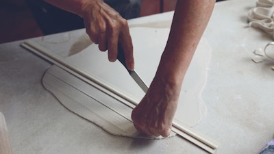 Cutting strips of clay.