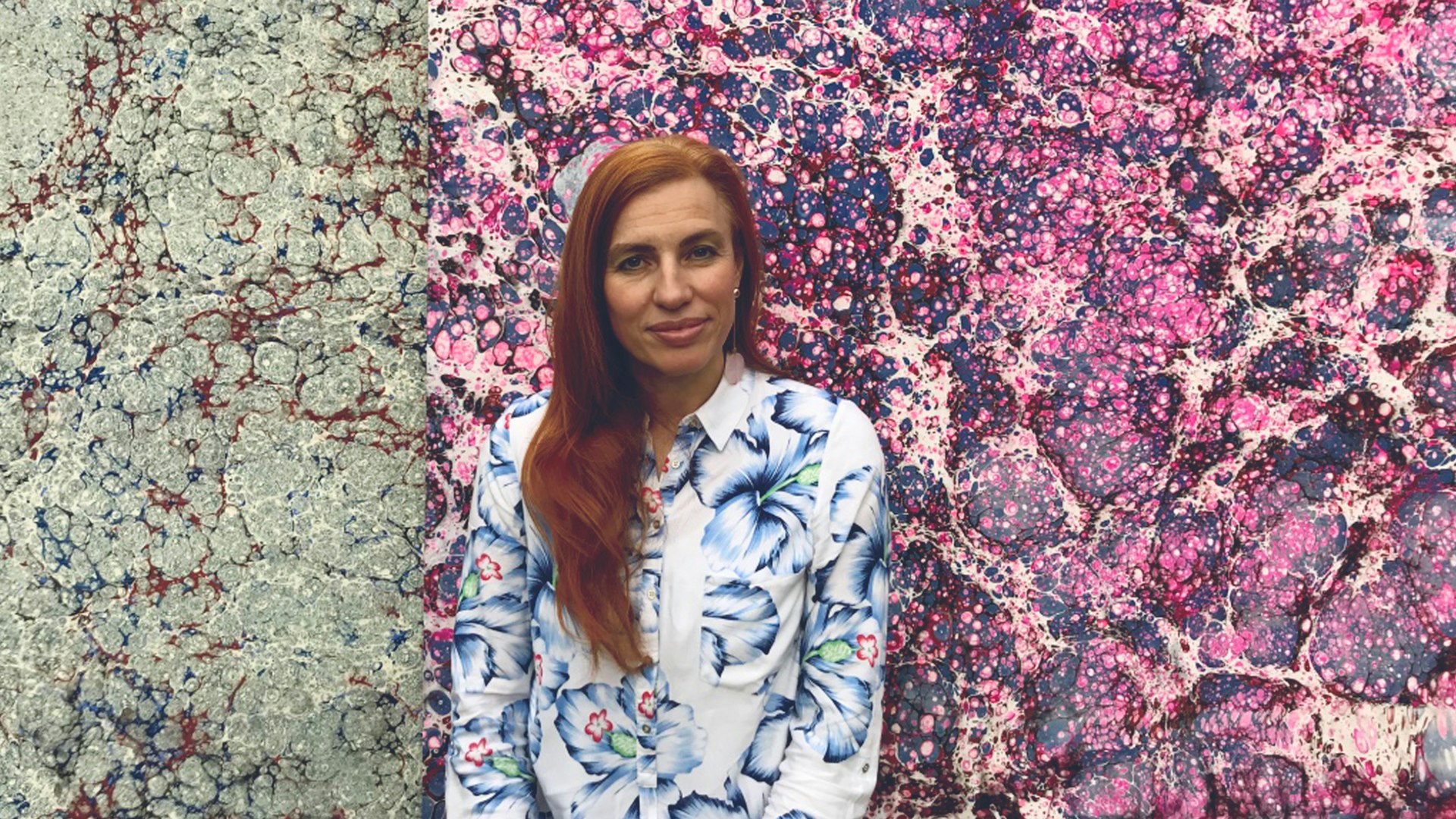 Artist facing the camera with a background of her Ebru Marbled paintings